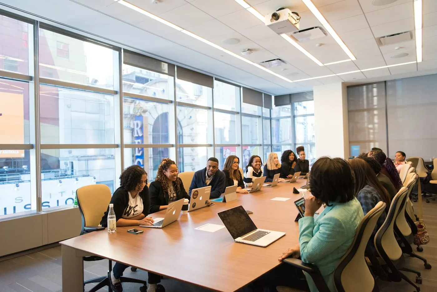 A team of professionals meeting around a long table with laptops