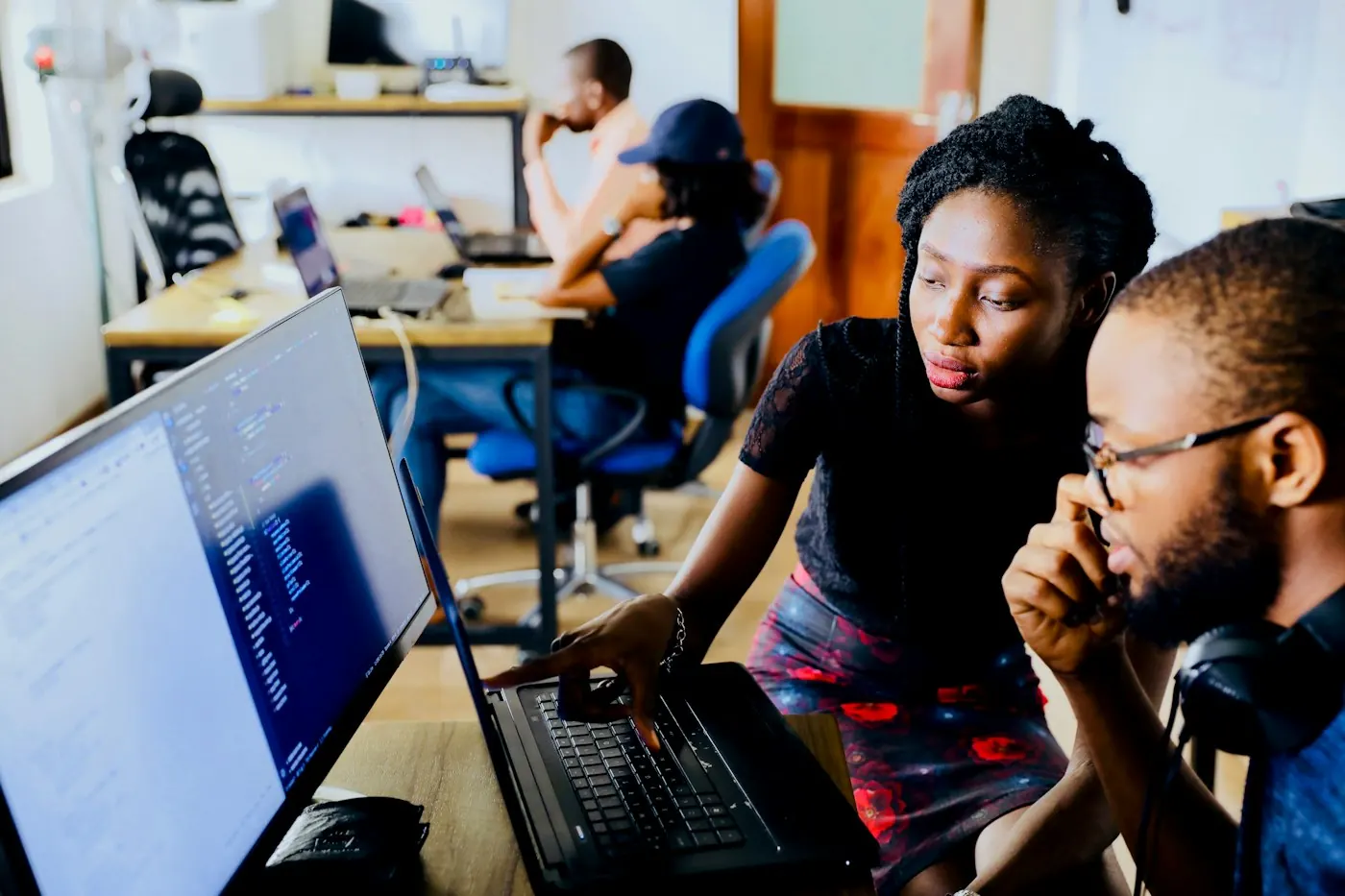 Two tech professionals reviewing code together at a workstation